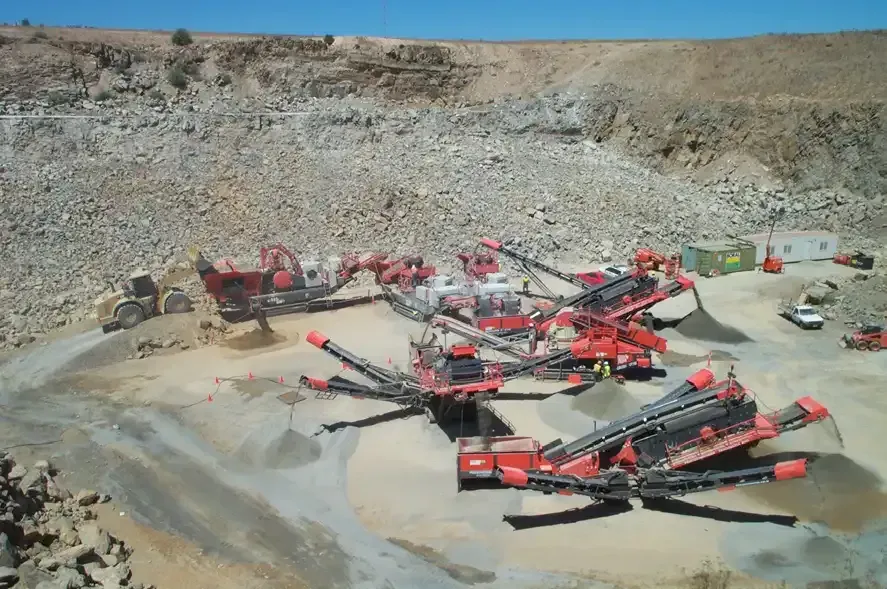 A lot of machinery is sitting on top of a dirt field