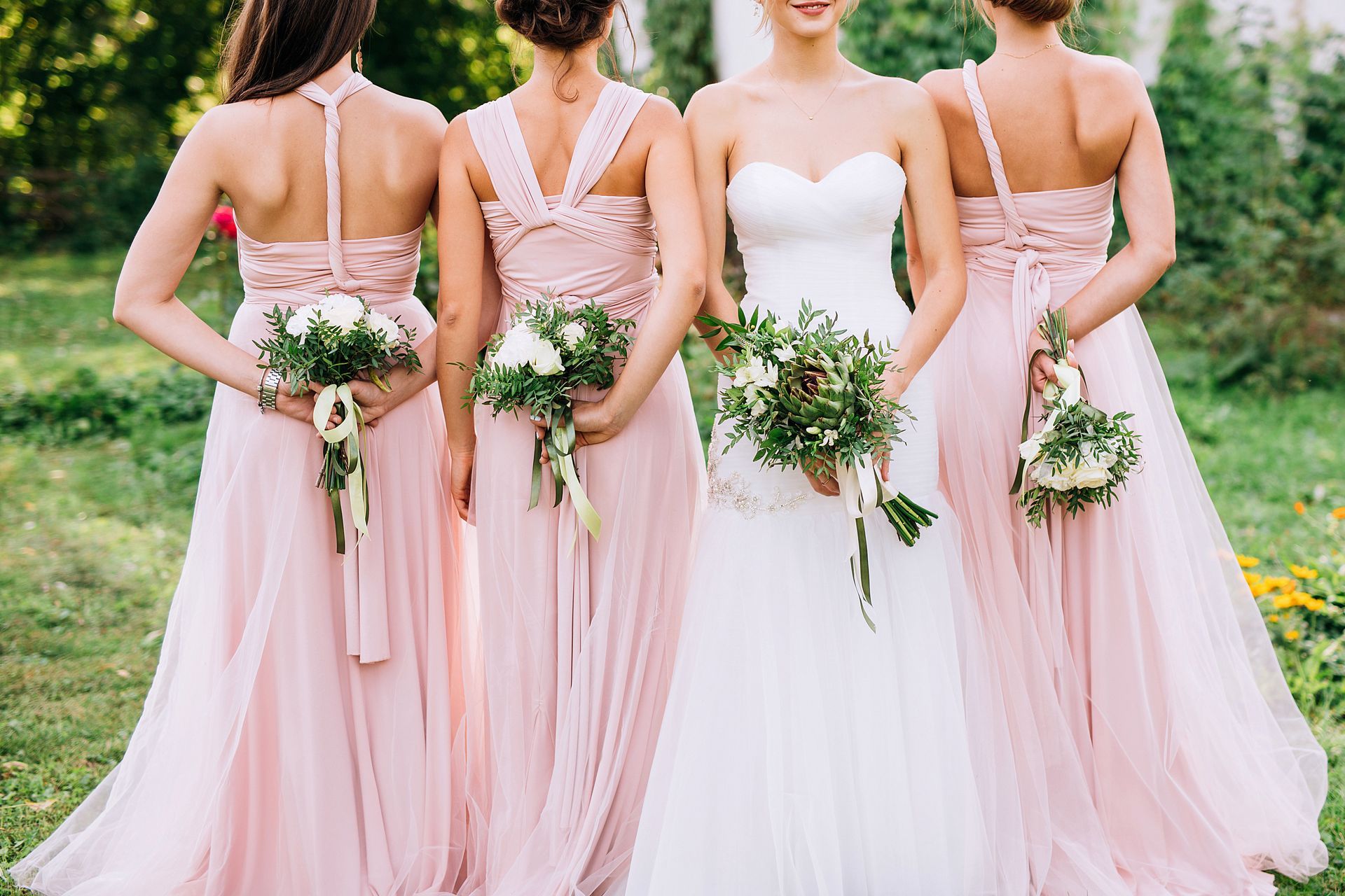 A bride and her bridesmaids are standing next to each other holding bouquets of flowers.