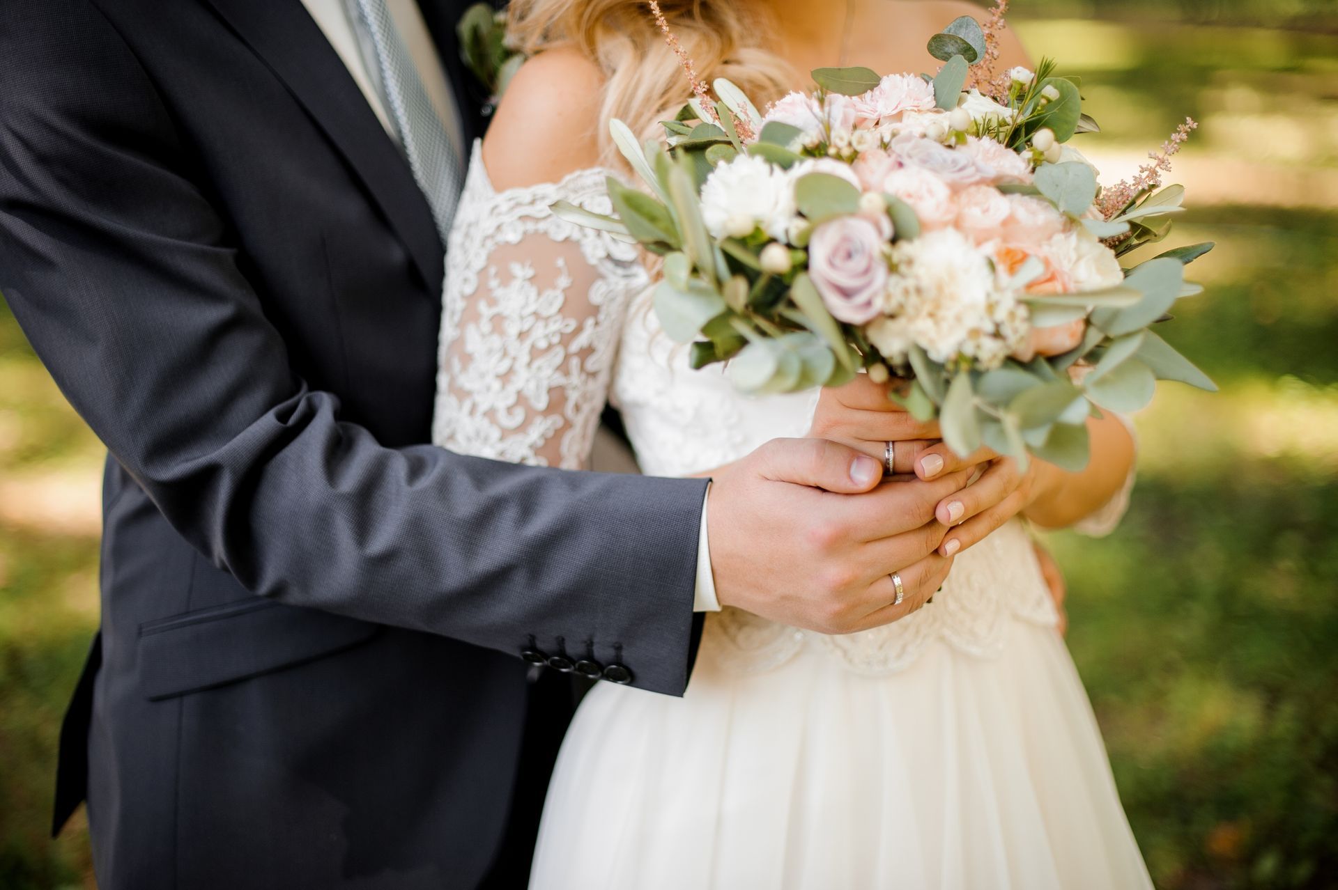 A bride and groom are holding hands and the bride is holding a bouquet of flowers.