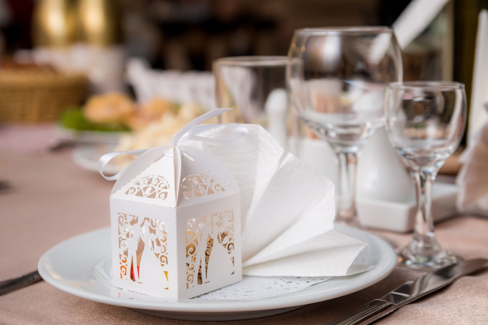 White favor box with bride and groom silhouette on a plate, set for a wedding reception.
