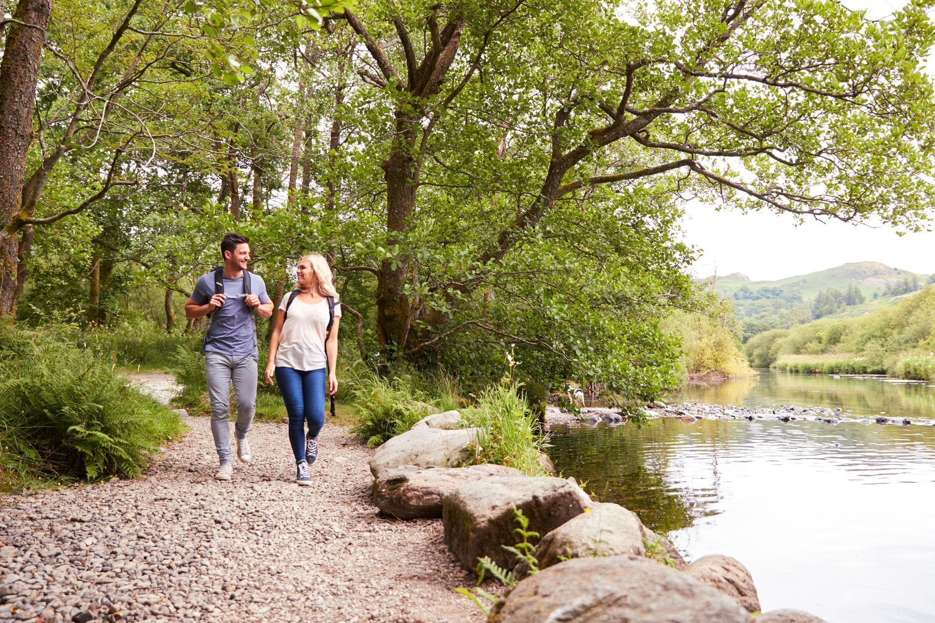 A man and a woman are walking along a path next to a river.