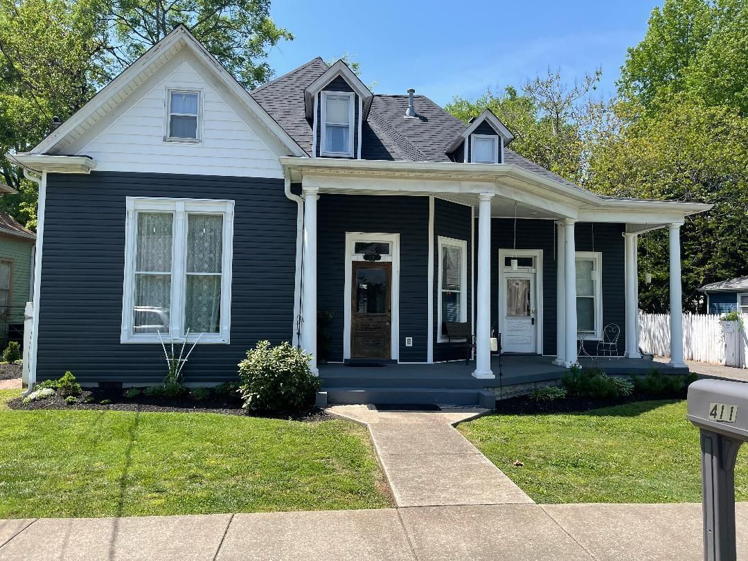 A black and white house with a porch on a sunny day.