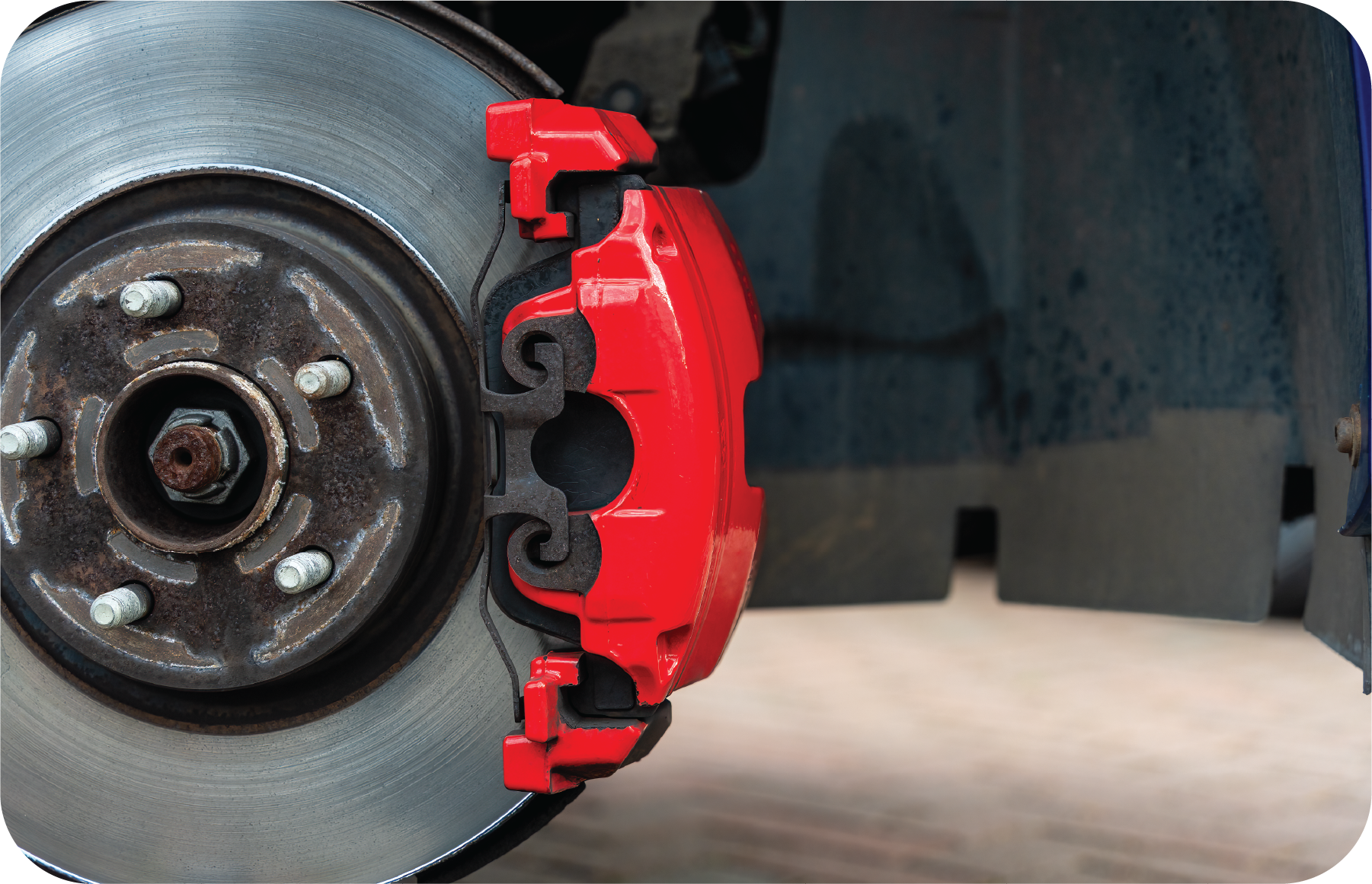 A close up of a red brake caliper on a car wheel.
