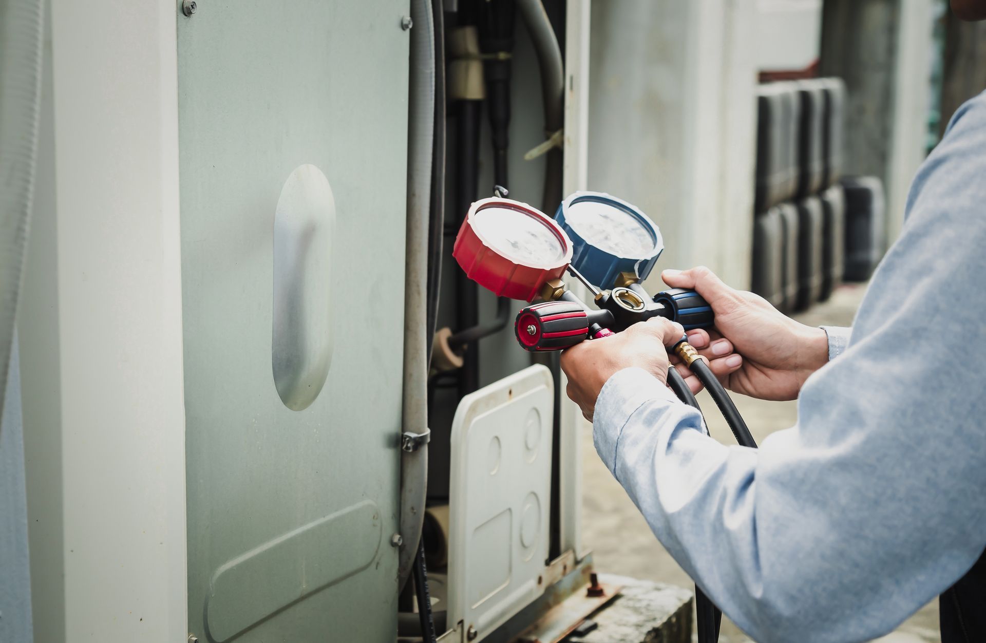 Person holding gauges, checking an air conditioning unit.