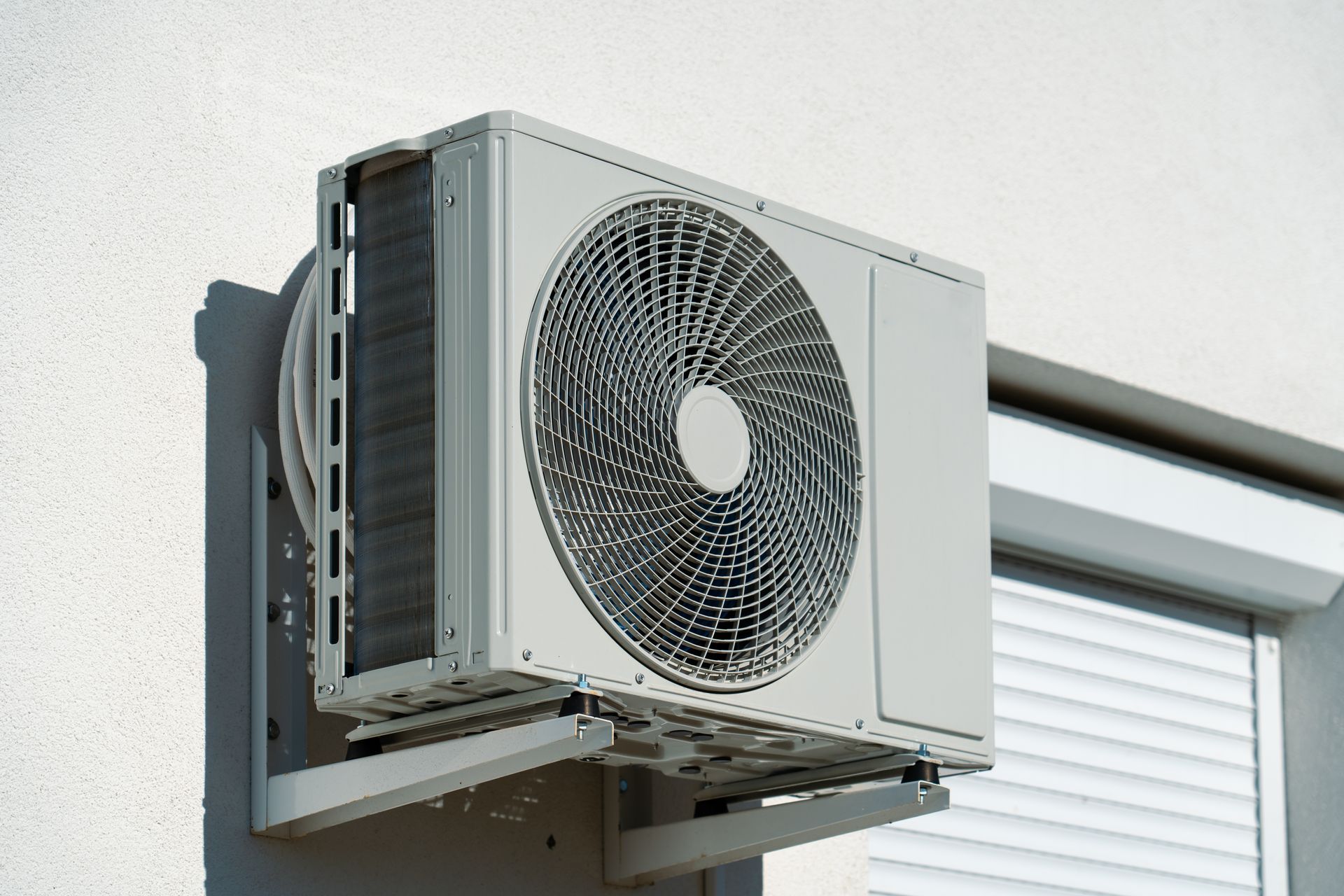 White air conditioning unit mounted on a white exterior wall.