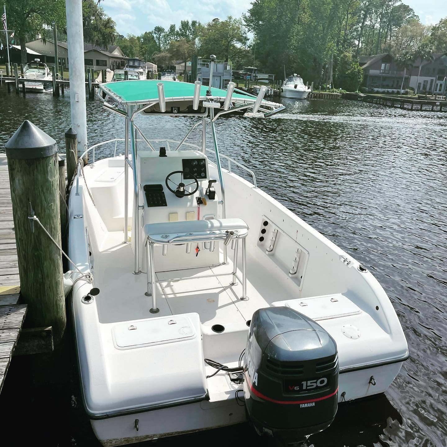 A white boat with a 150 engine is docked at a dock