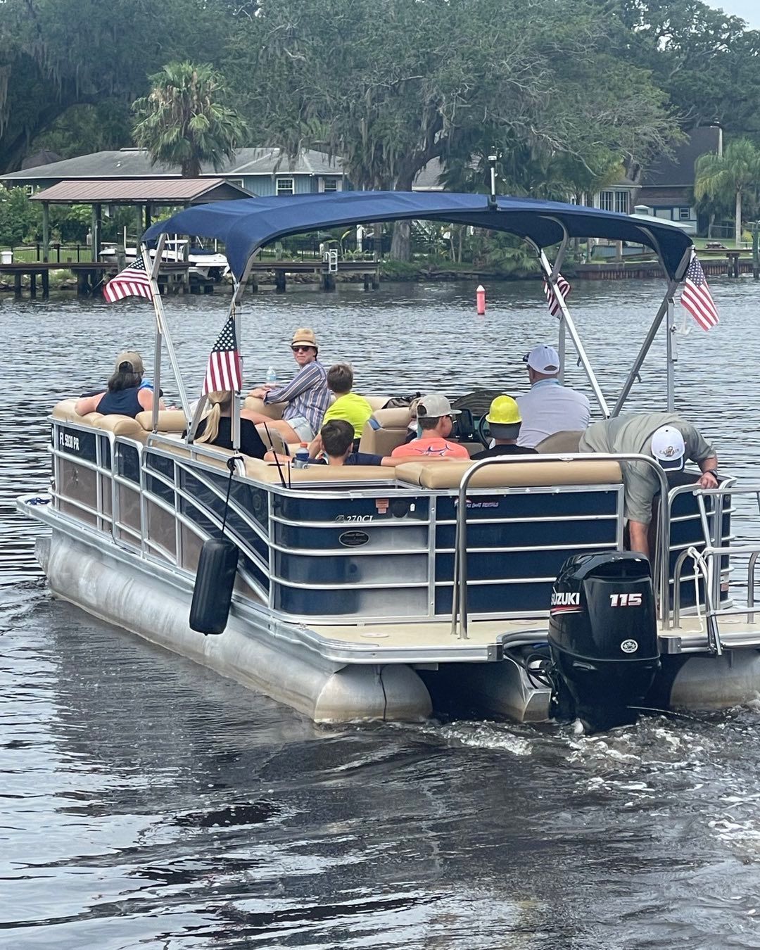 A group of people are riding a pontoon boat on a lake.