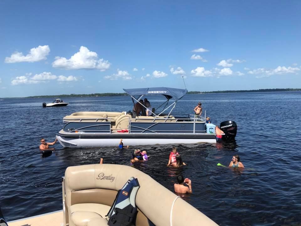 A group of people are swimming in the water on a pontoon boat.