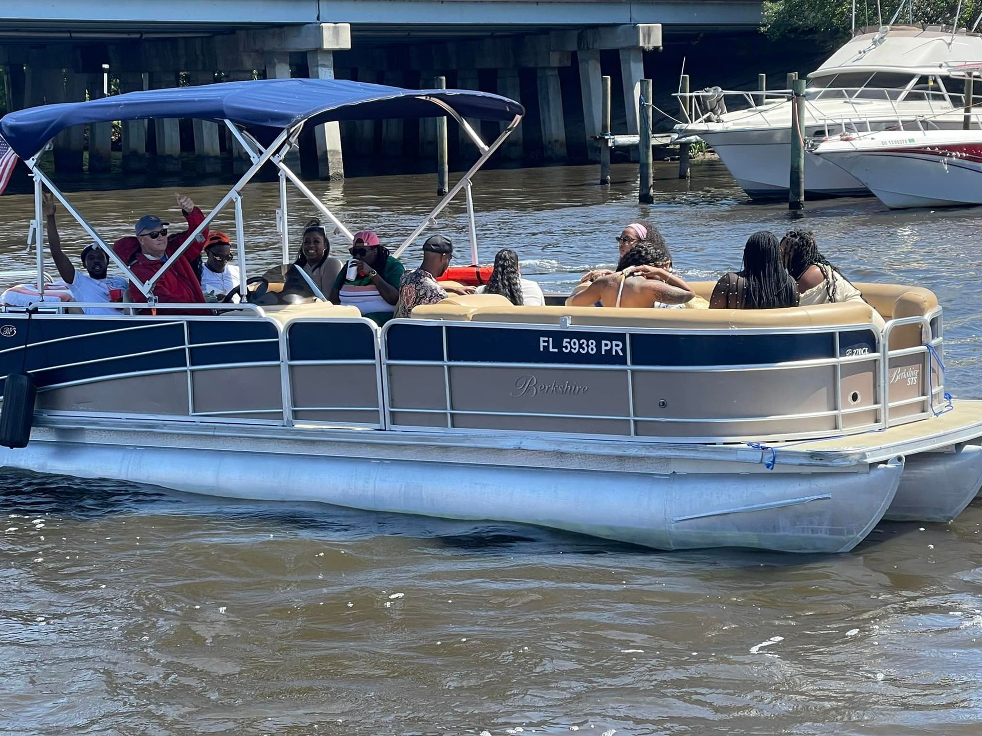A group of people are riding a pontoon boat on a river.