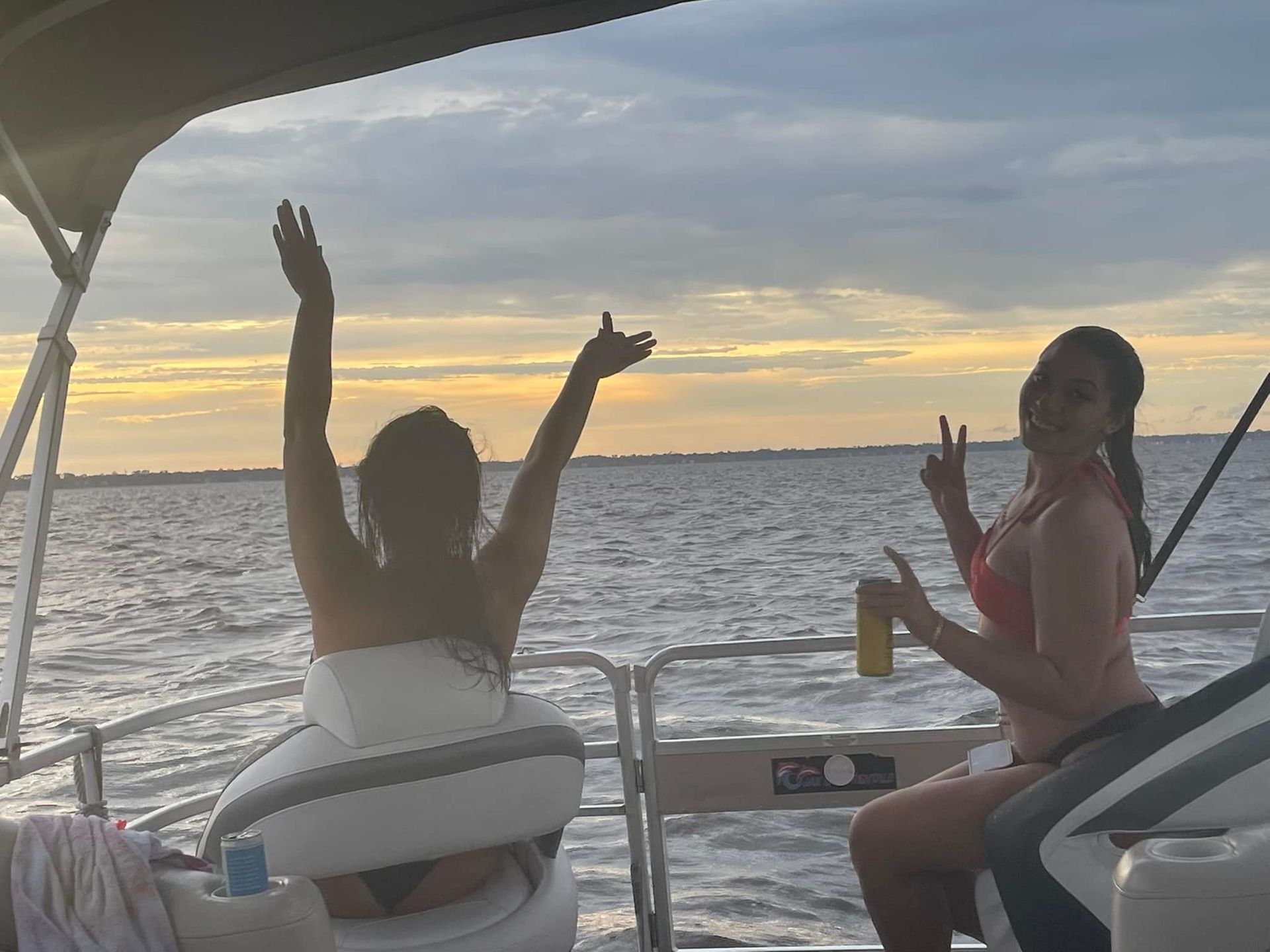 Two women are sitting on a boat with their arms in the air.