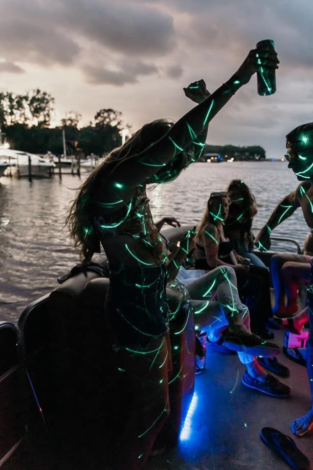A group of people are sitting on a boat with neon lights on their bodies.