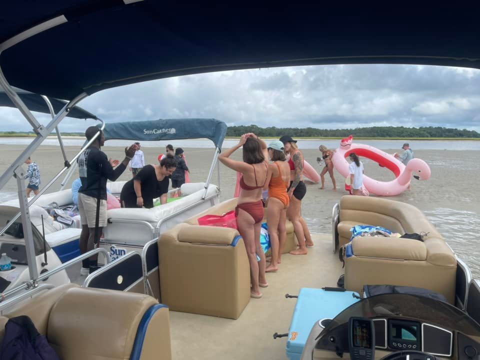 A group of people are standing on a pontoon boat.