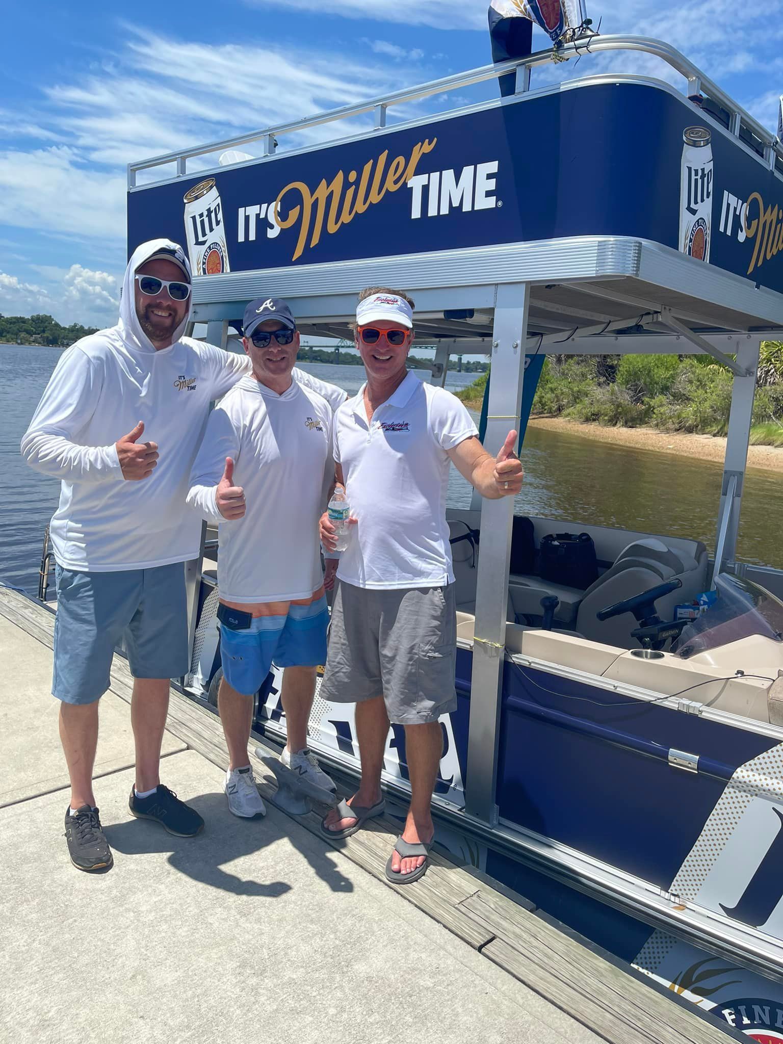 Three men are standing in front of a boat that says miller time.