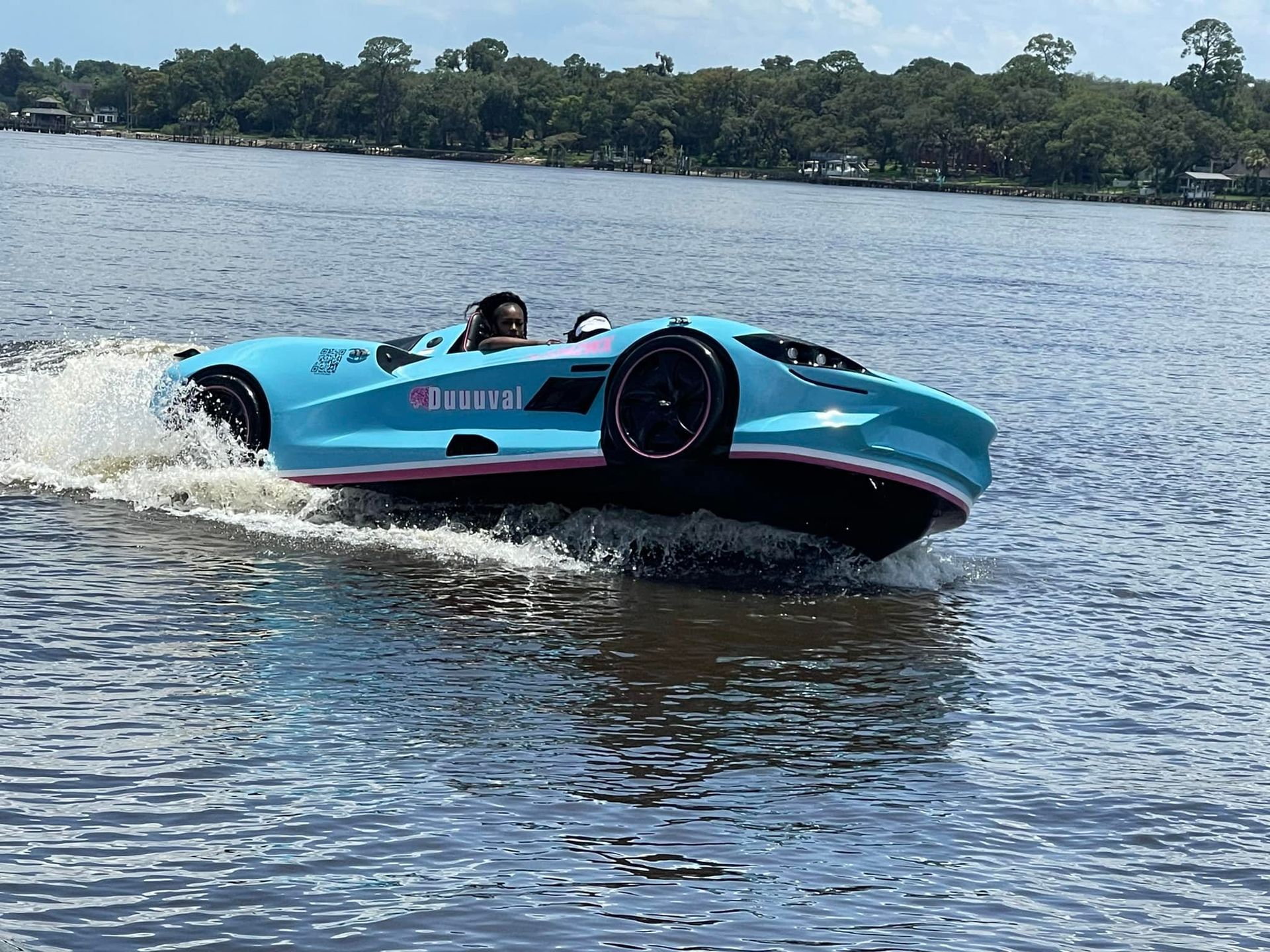 A blue and pink sports car is floating on top of a body of water.