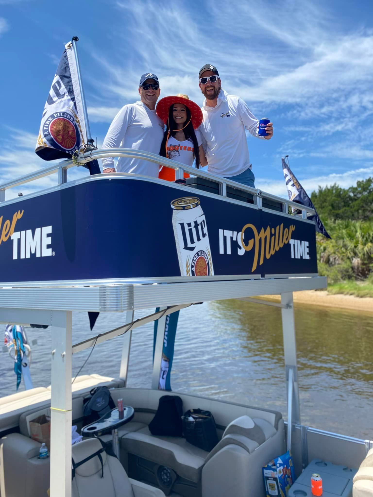 A group of people are standing on top of a pontoon boat.
