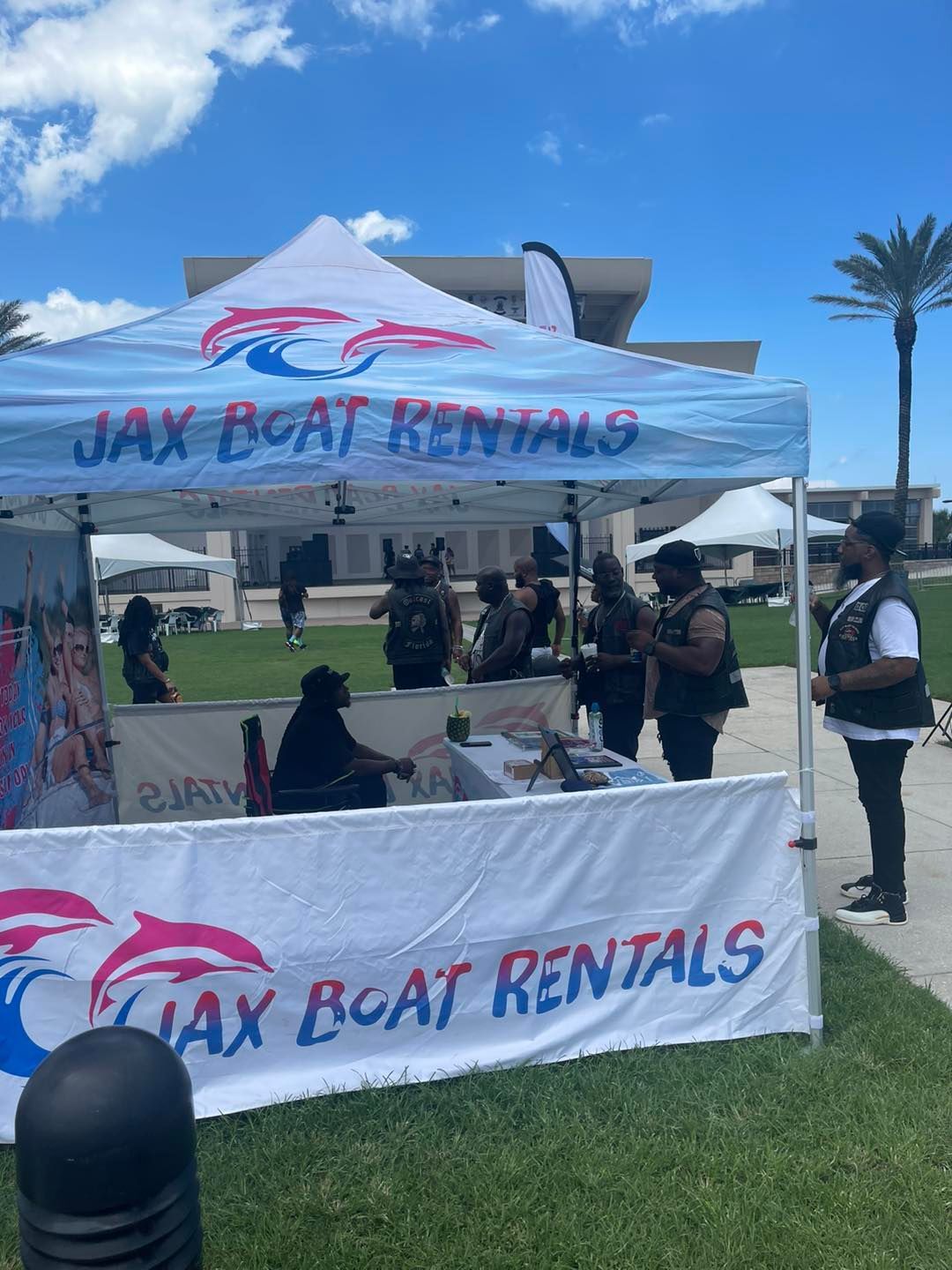 A group of people are standing around a tent that says jax boat rentals.