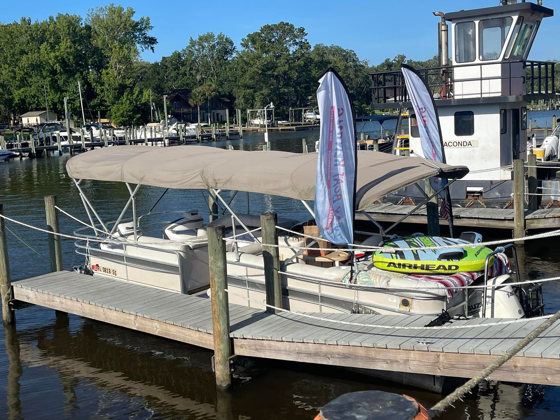 A pontoon boat with a canopy is docked at a dock.