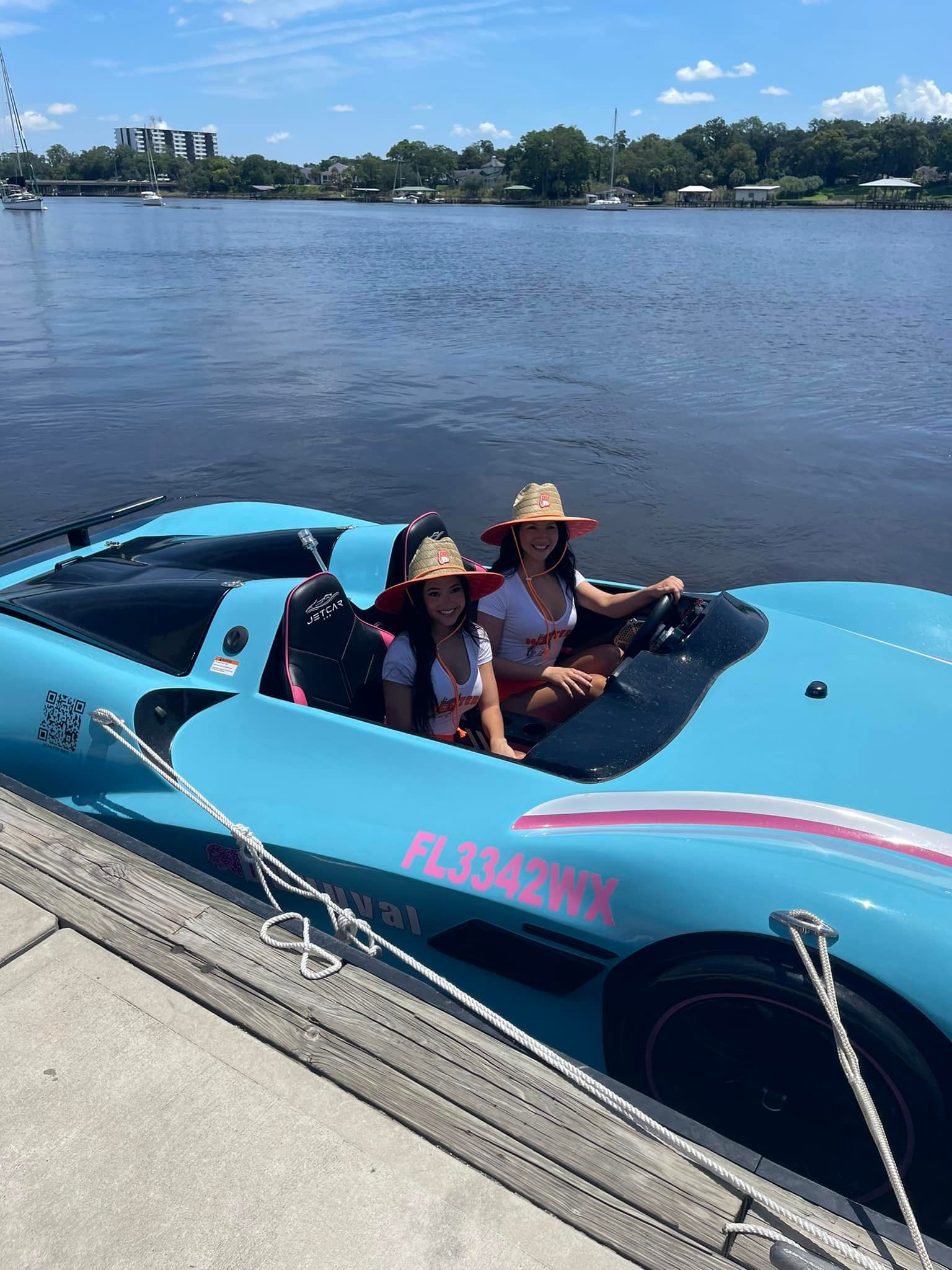 Two women are sitting in a blue speed boat on a lake.