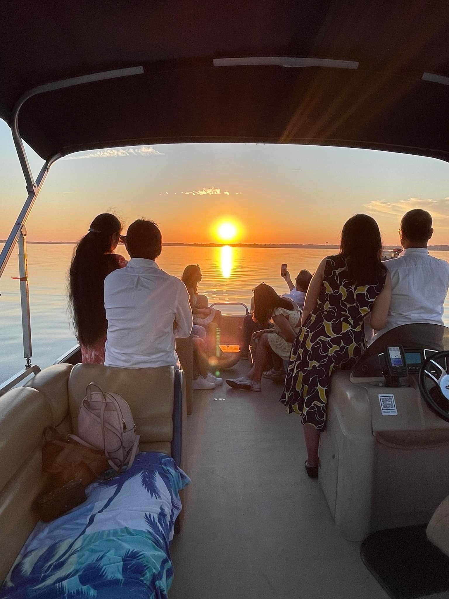 A group of people are sitting on a boat watching the sunset.