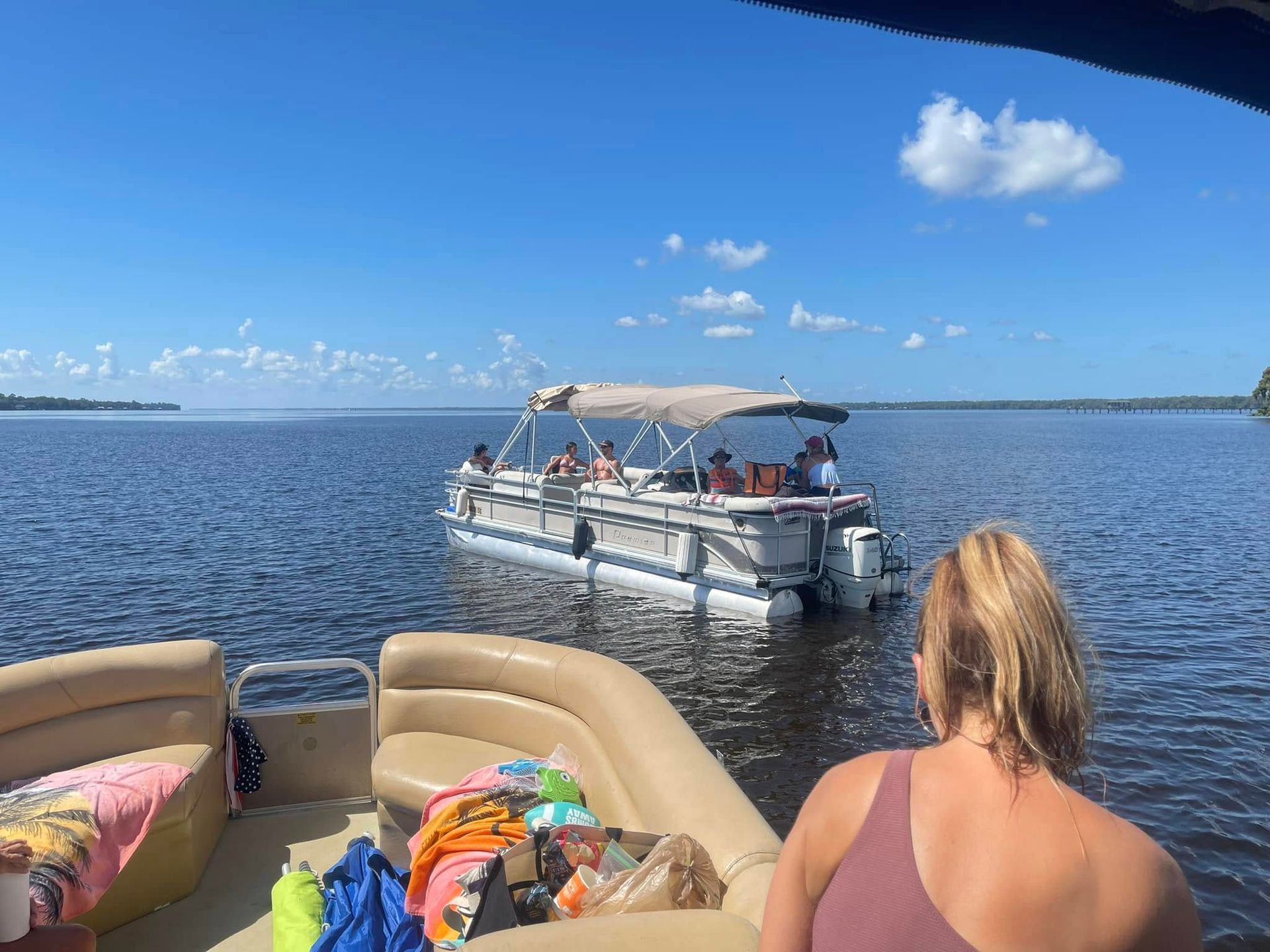 A woman is sitting on a pontoon boat on a lake.