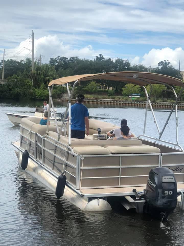 A man is standing on a pontoon boat in the water.