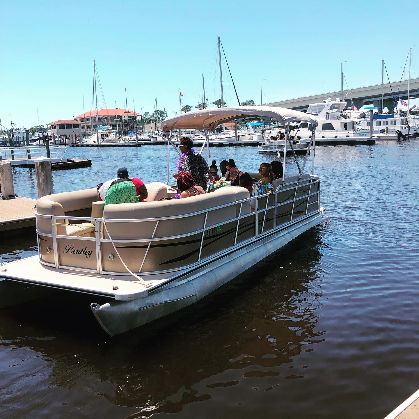 A group of people are on a pontoon boat in the water.