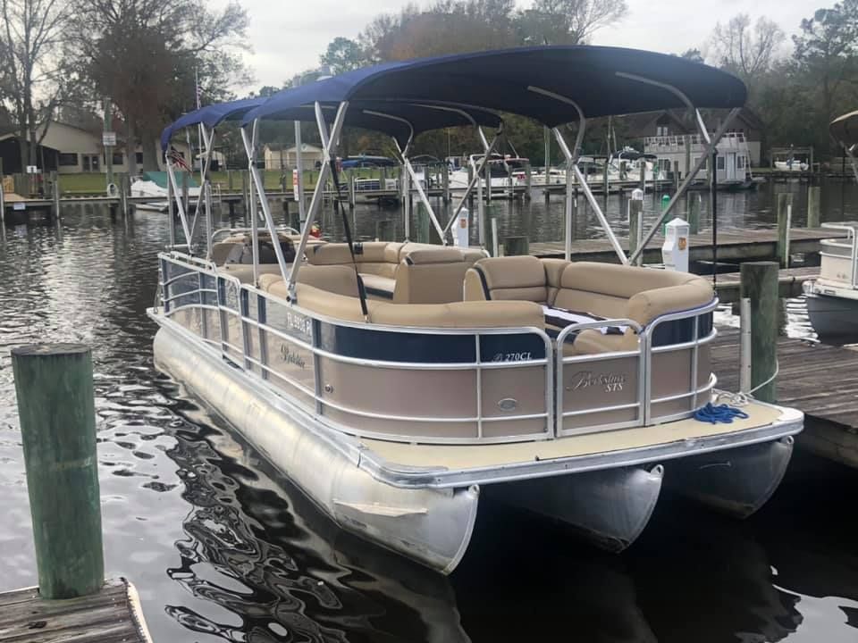 A pontoon boat is docked at a dock on a lake.