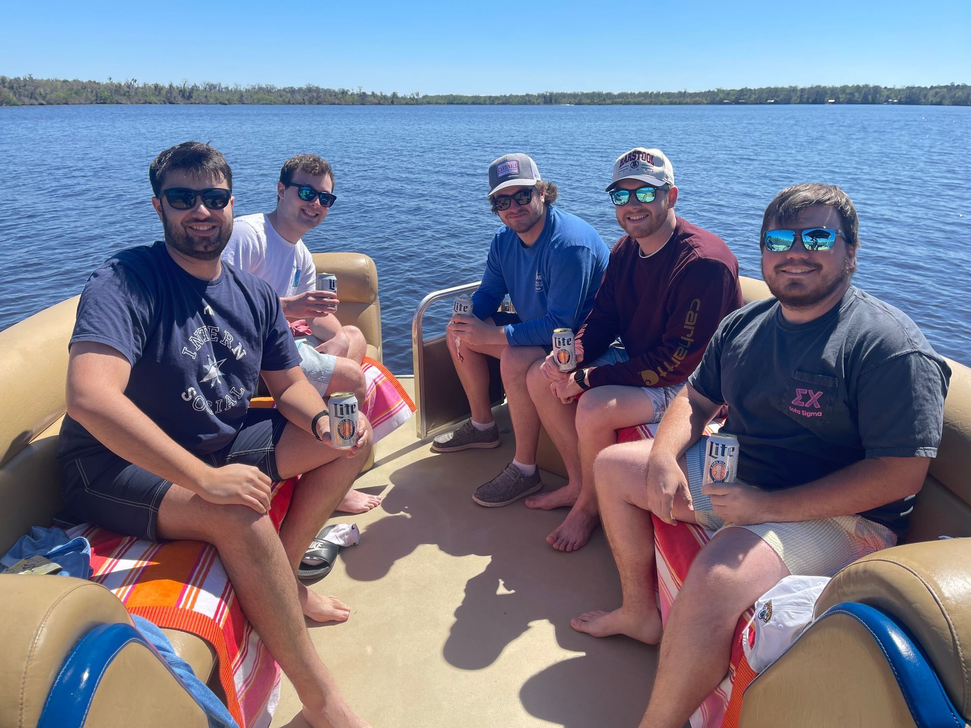 A group of men are sitting on a pontoon boat on a lake.