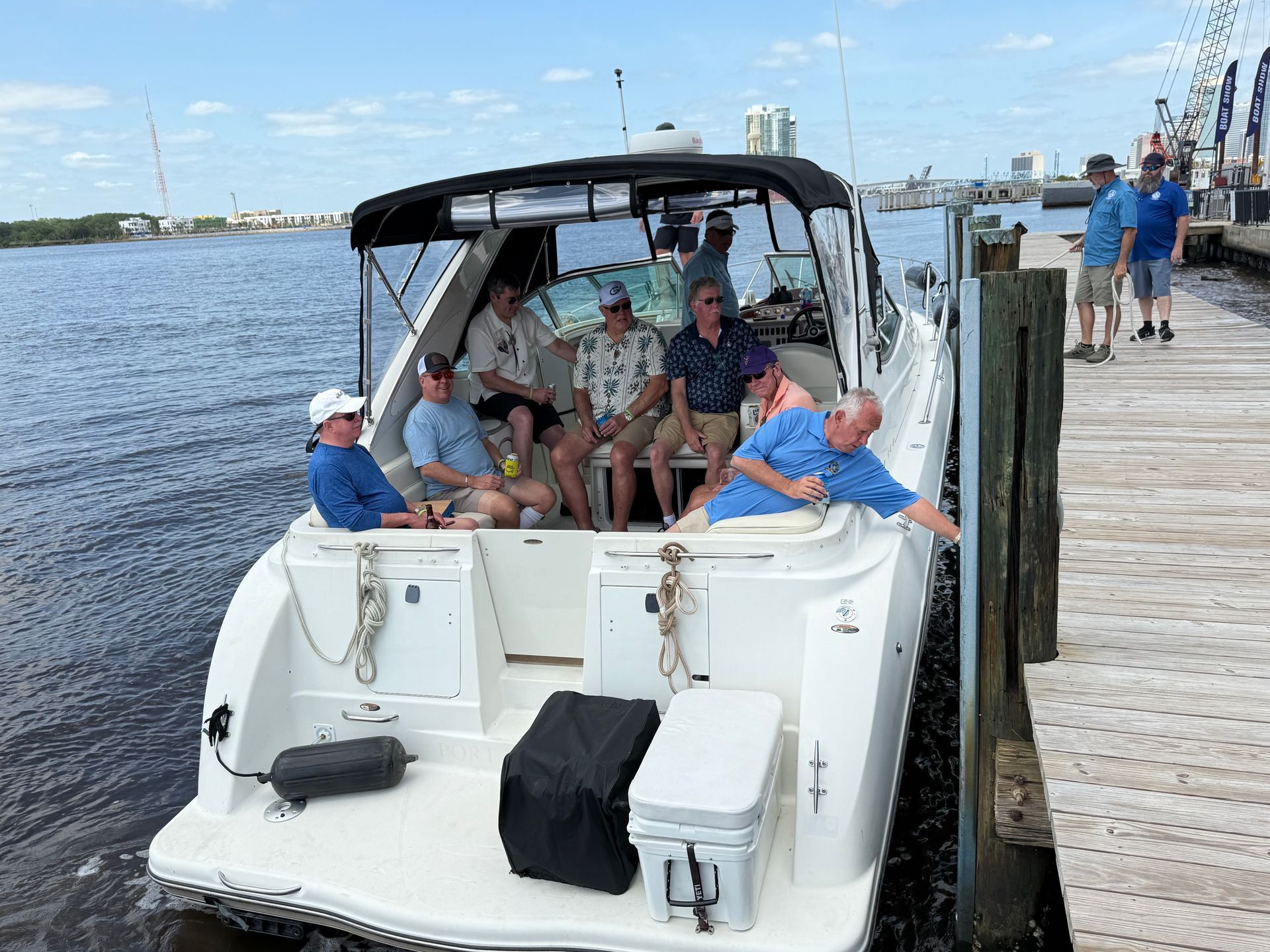 A group of men are sitting on the back of a boat.