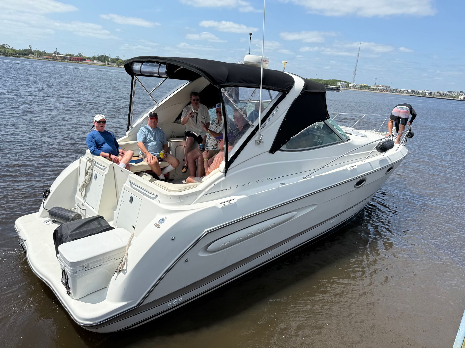 A group of people are sitting on a white boat in the water.