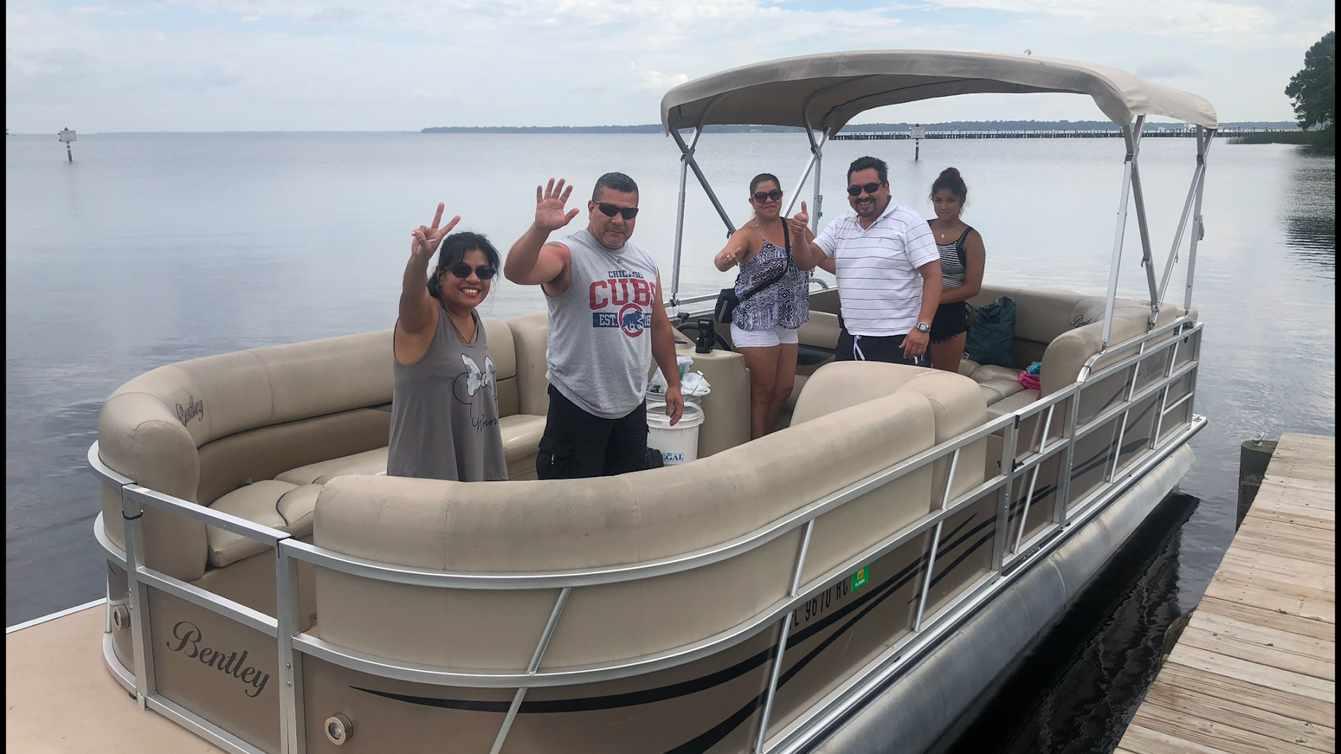 A group of people are standing on a pontoon boat.