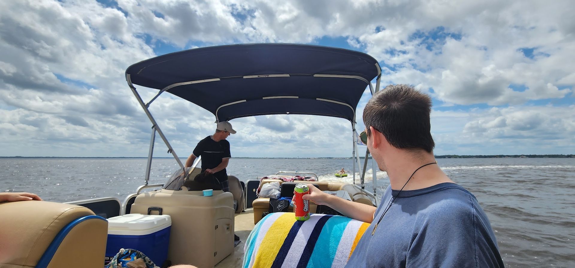A man is standing on a pontoon boat in the water.