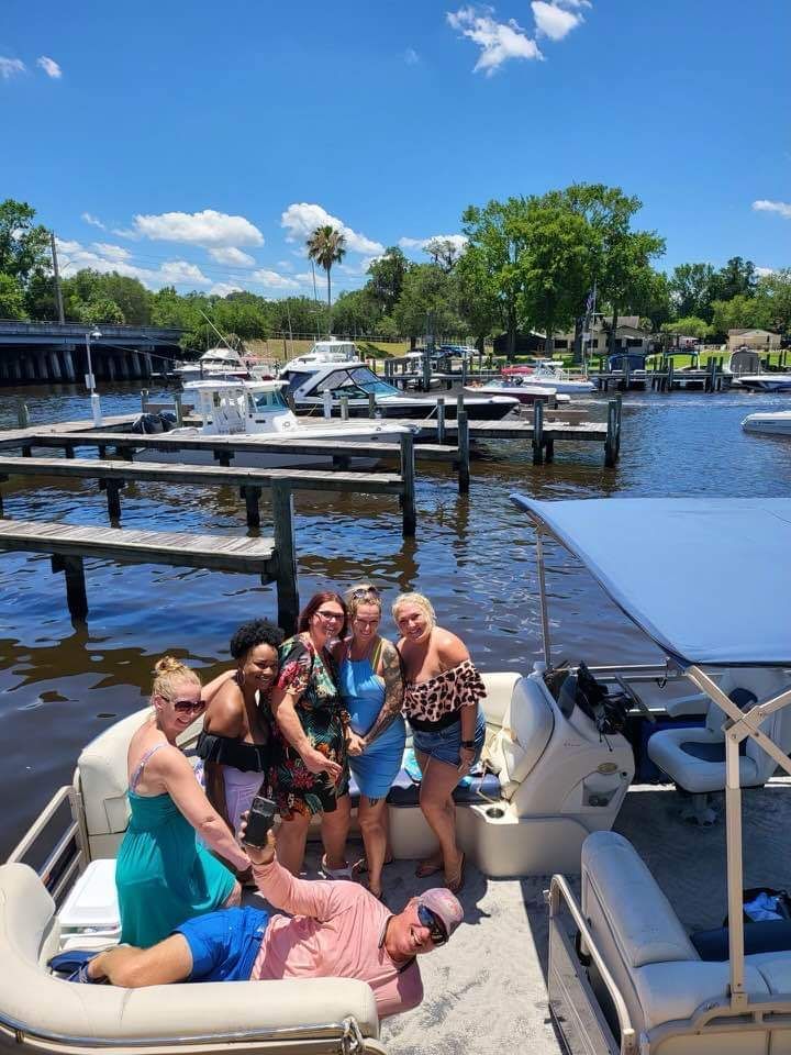 A group of people are posing for a picture on a pontoon boat.