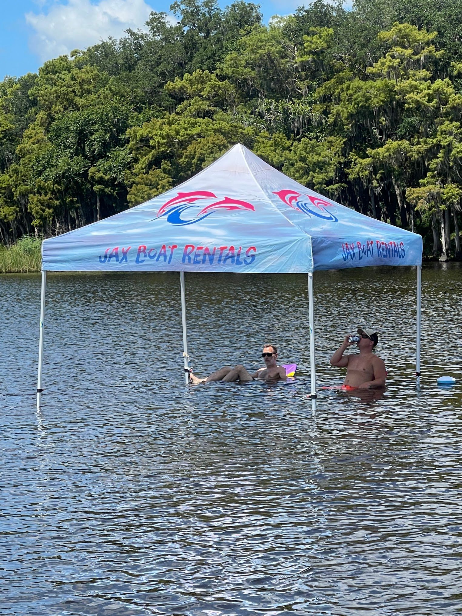 Two people are laying under a tent in the water.
