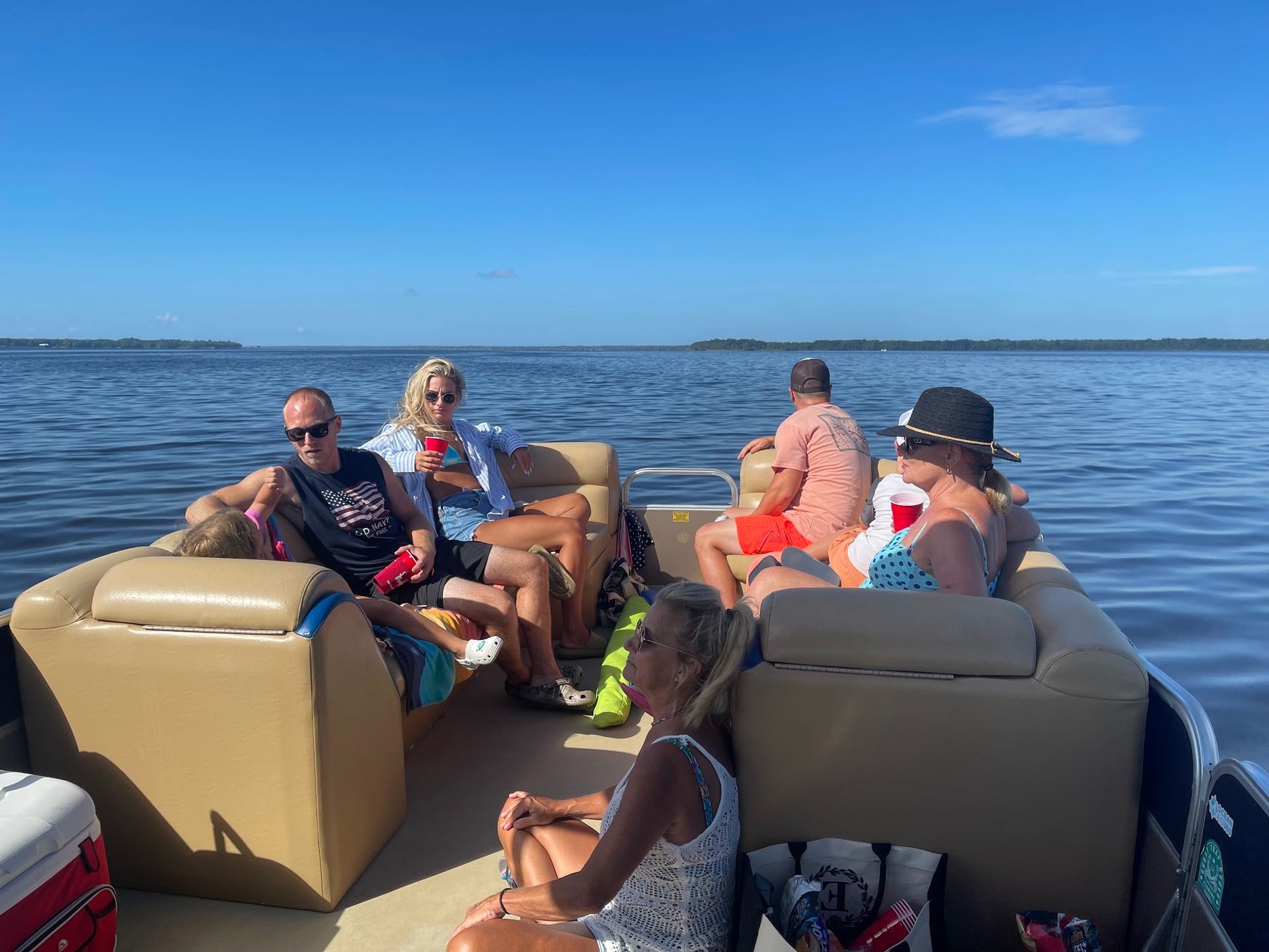 A group of people are sitting on a pontoon boat on a lake.