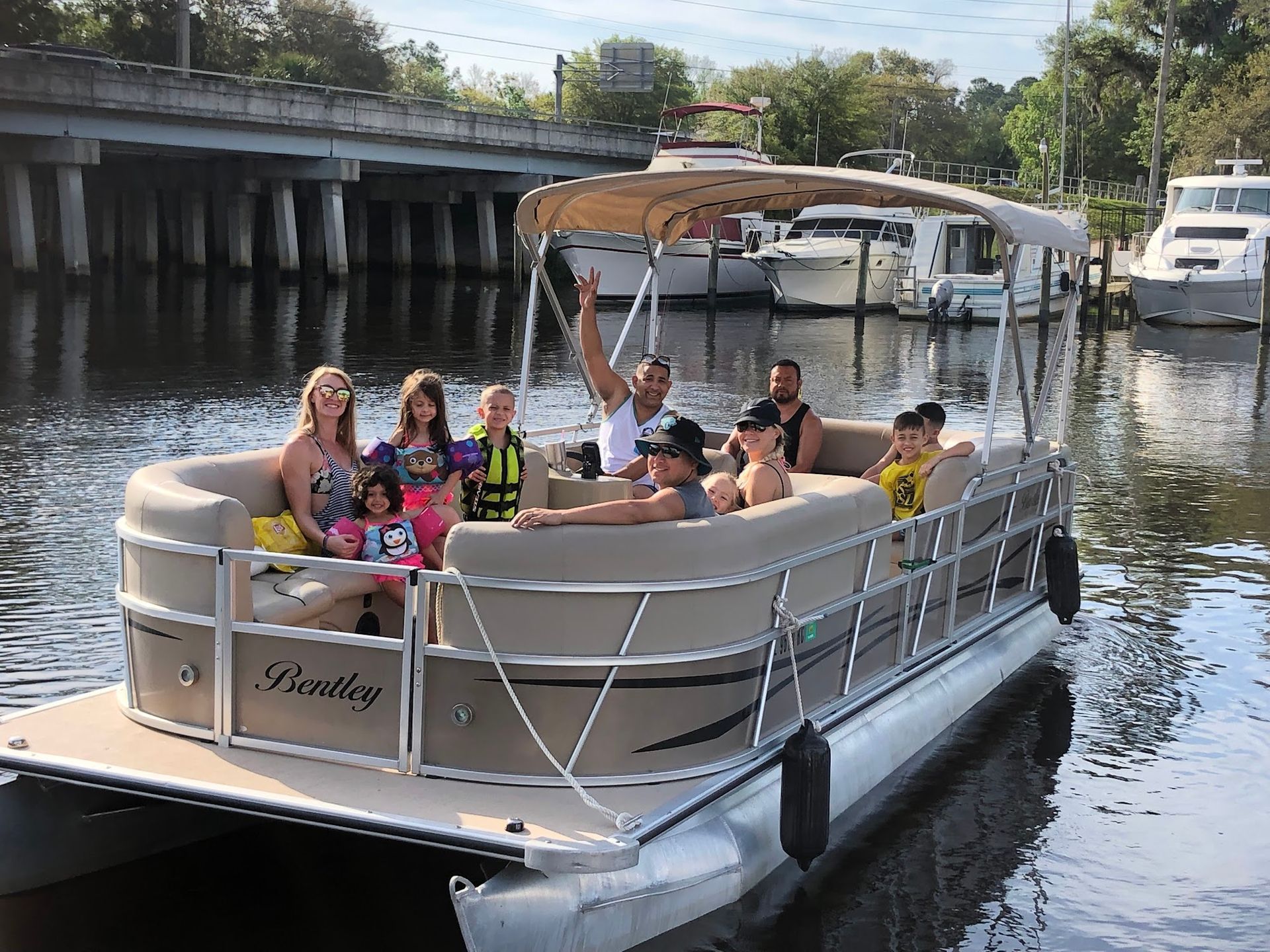A group of people are riding a pontoon boat on a river.