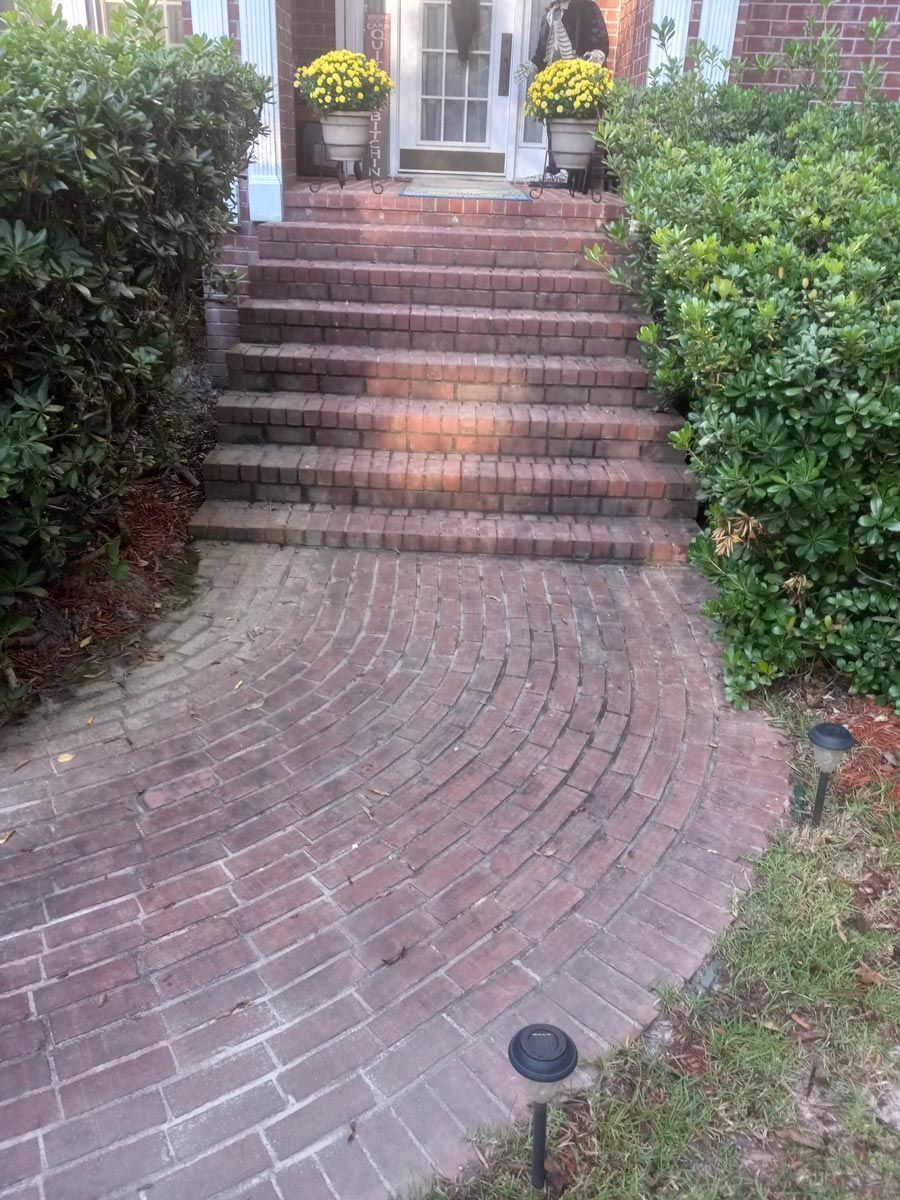 A brick walkway leading to the front door of a house.