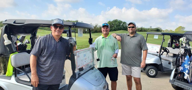 Three men are standing next to golf carts on a golf course.