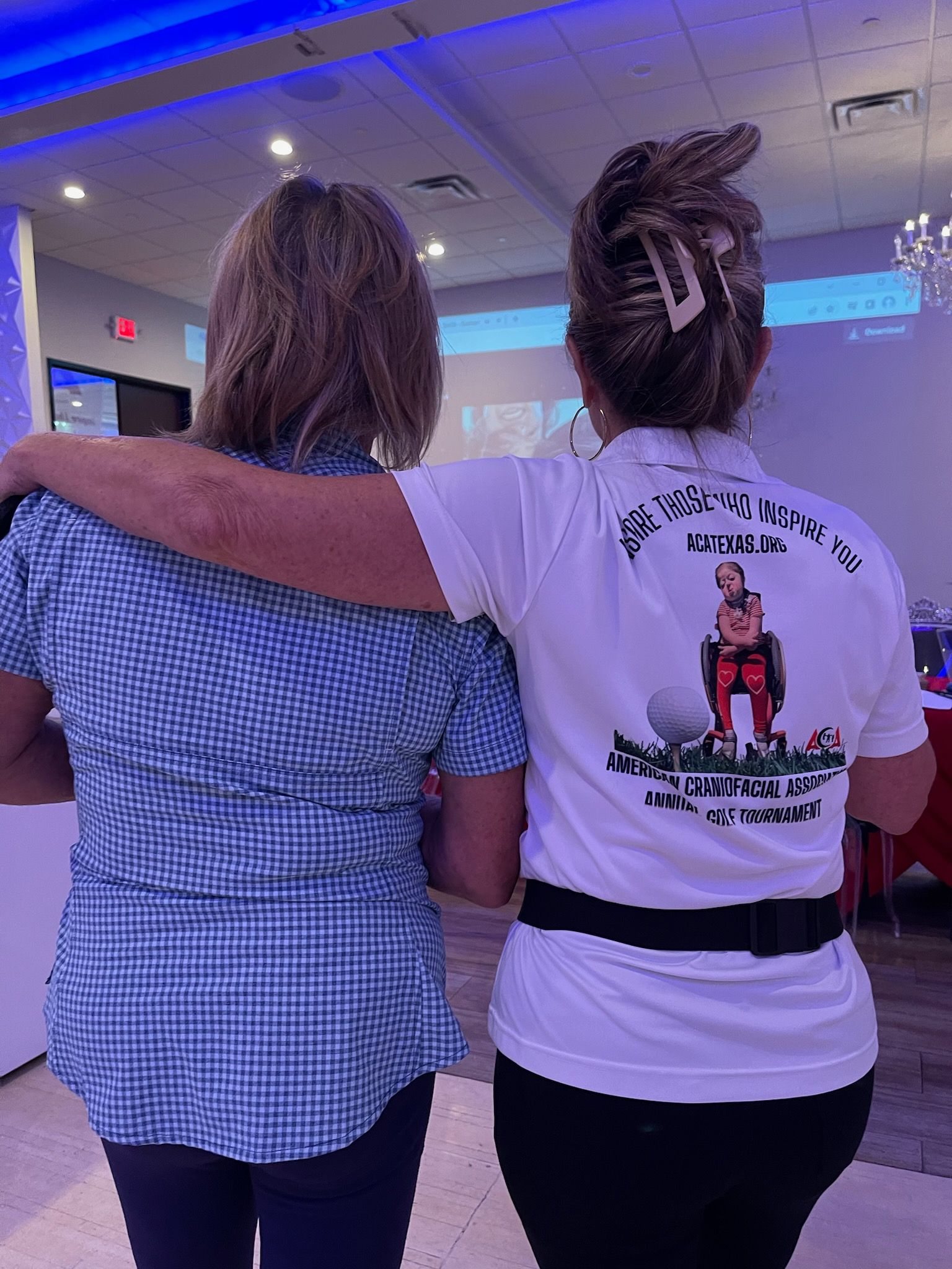 Two women are standing next to each other with their arms around each other.