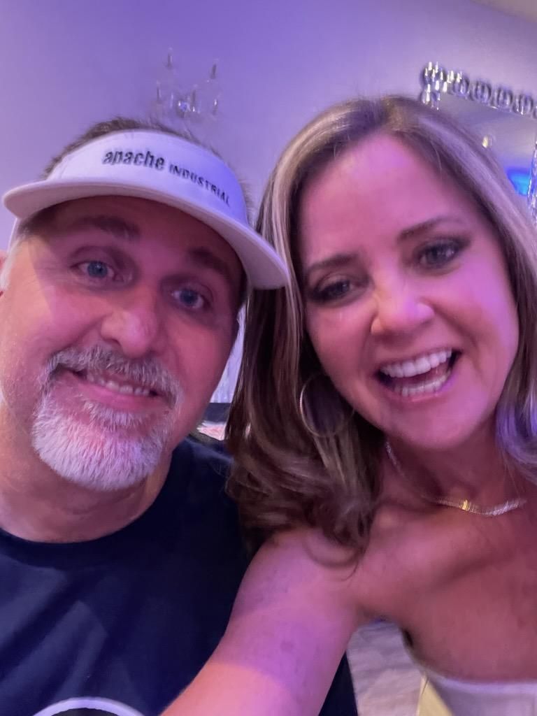 A man and a woman are posing for a picture and smiling for the camera.