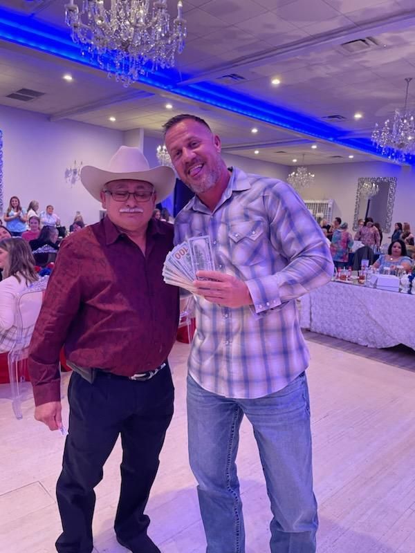 Two men are standing next to each other in a room holding money.