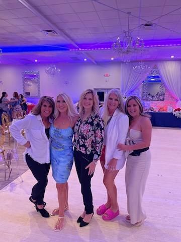 A group of women are posing for a picture in a room with purple lights.