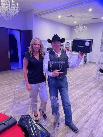 A man in a cowboy hat is standing next to a woman in a room holding a box.