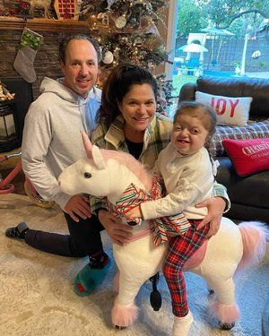 A family is posing for a picture while a little girl is riding a unicorn.