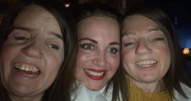 Three women are posing for a picture together and smiling.