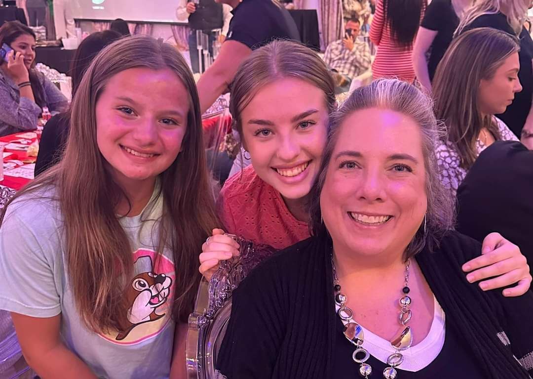 A woman and two girls are posing for a picture at a party.