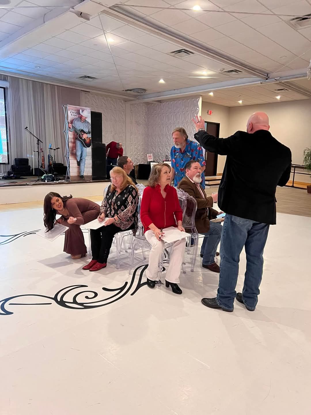 A man is standing in front of a group of people sitting in chairs in a room.
