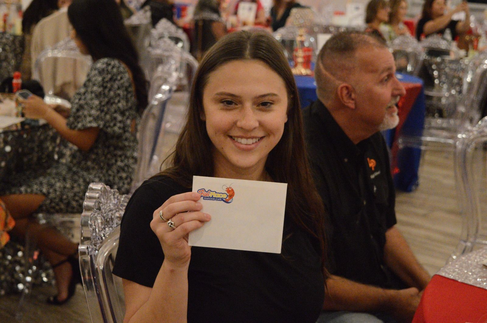 A woman is holding a piece of paper with the word pizza on it.