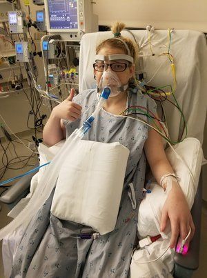 A woman is laying in a hospital bed with an oxygen mask on her face.