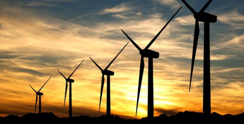 a row of wind turbines against a sunset sky